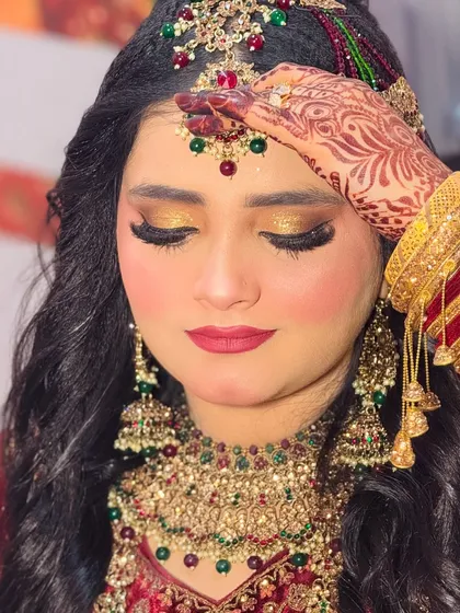 A close-up of this beautiful bride's royal look for her Walima. The golden glitter eyeshadow is the star of the show, paired with a deep red lip and flawless skin.