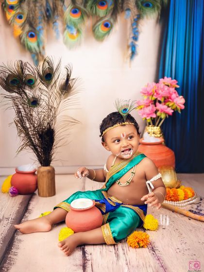 A candid and adorable shot of a little boy dressed as Krishna, caught making a mischievous face. It's a perfect capture of childhood innocence and playfulness.