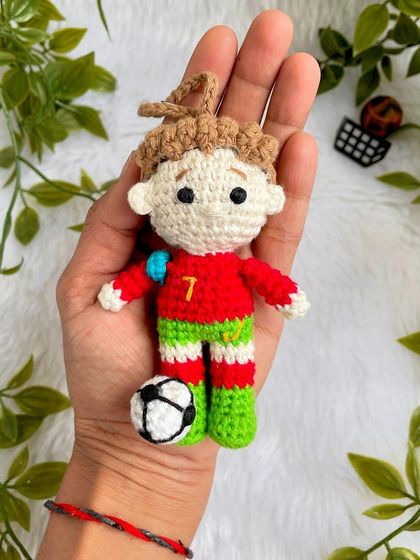 A mini replica doll of the football superstar Cristiano Ronaldo, CR7! This keychain-sized doll is ready for the field with his jersey and a tiny football.
