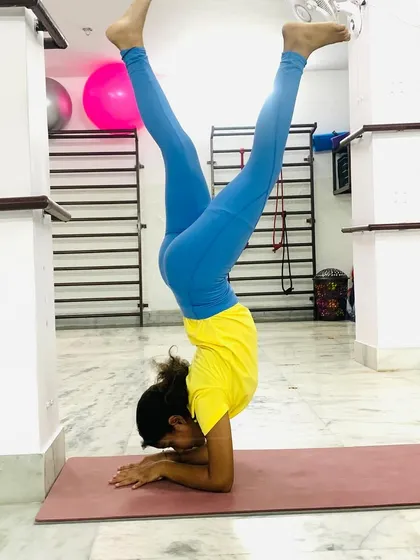 This student is gracefully holding Pincha Mayurasana (Forearm Stand), an inversion that strengthens the shoulders, arms, and back while improving balance.