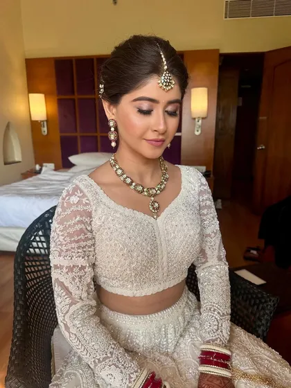 A close-up of a bride's serene expression, her hair styled in a neat, traditional bun. This look is perfect for a daytime wedding, offering a fresh and timeless feel.