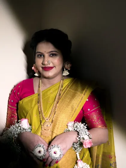 A beautifully lit portrait of the mother-to-be, showcasing her traditional look for the Dohale Jevan. The dramatic lighting highlights her serene expression, elegant saree, and the delicate floral jewelry she wears.