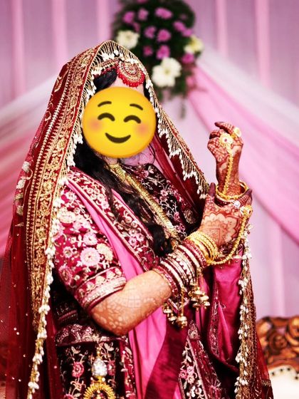 A happy bride showing off her full bridal look, with her dark henna stain adding to her beauty.