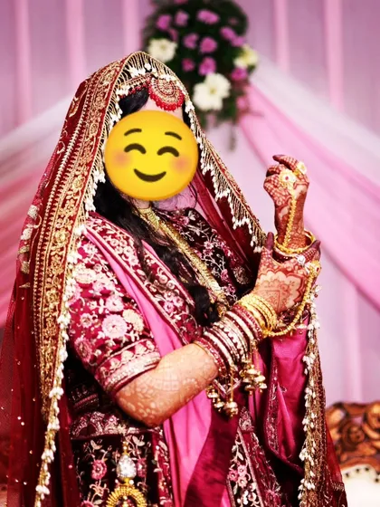 A happy bride showing off her full bridal look, with her dark henna stain adding to her beauty.