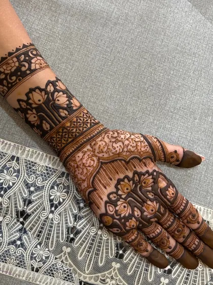 The beauty of a freshly completed design. This back-of-hand mehendi features intricate lotus motifs, with the rich, dark henna paste ready to work its magic.
