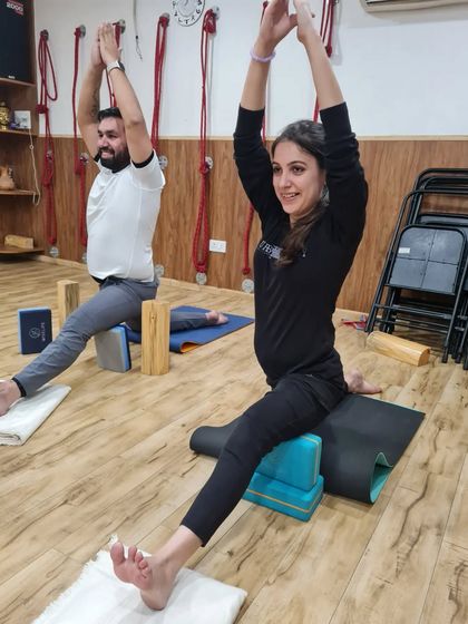 A student works on Hanumanasana (the splits) using blocks for support. This is a great way to gradually open the hips and hamstrings without forcing the body.