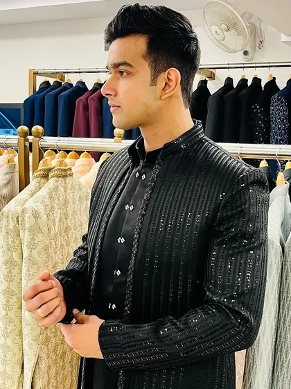 A client trying on a black sequined Indo-western jacket set, perfect for a glamorous sangeet night or cocktail party.