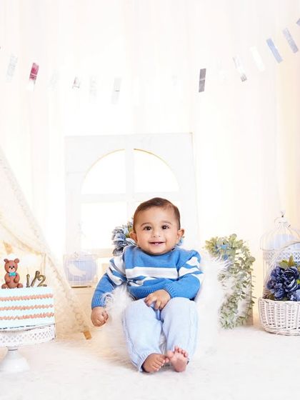 A six-month "halfway to one" celebration! This baby boy is all smiles in a blue-themed setup with a teepee, cake, and "BABY" blocks.