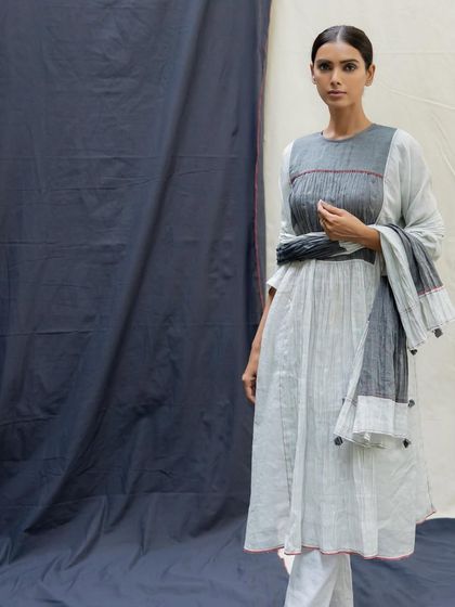 An elegant light grey pleated kurta set with a textured yoke and a matching dupatta, a perfect blend of comfort and style.