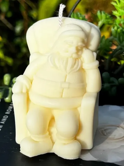 Santa is taking a well-deserved nap in this charming Christmas candle. This snoozing Santa in his armchair is a whimsical decorative piece, handcrafted from 100% soy wax for the holiday season.