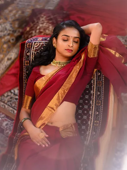 A serene, artistic pose capturing the model in a moment of quiet elegance. The use of traditional carpets and soft lighting creates a warm and inviting atmosphere.