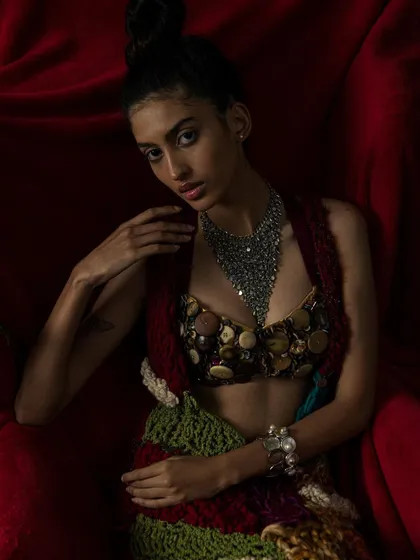 This editorial shoot was a feast of textures. The rich red velvet chair complements the bohemian, handcrafted feel of the designer outfit.
