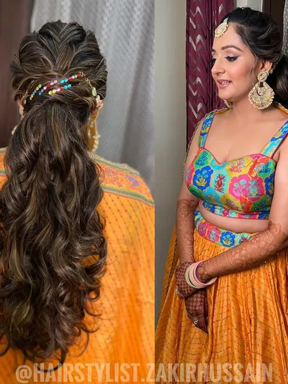 A fun and festive ponytail for a Mehendi ceremony, featuring a braided crown and colorful bead accessories. The soft waves add a playful touch to this vibrant look.