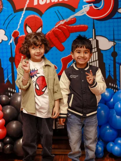 Two friends celebrate a Spider-Man themed birthday, posing in front of the city skyline backdrop. Our parties are a great place for kids to bond and share their interests.