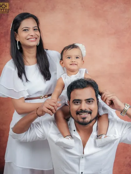 A playful family portrait with the little one enjoying a ride on her father's shoulders.