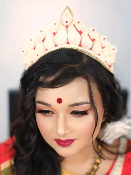 The quintessential Bengali bride. This close-up focuses on the traditional 'mukut' and the intricate 'chandan' designs, capturing the serene beauty of bridal traditions.