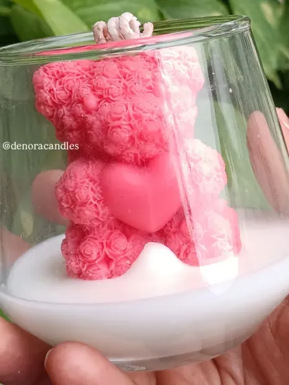 A close-up of the pink rose-textured teddy bear candle in a glass jar.