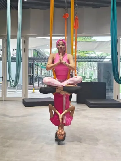 The final variation of the partner lotus pose, capturing a moment of perfect symmetry and shared focus between the two aerialists in our sunlit studio.