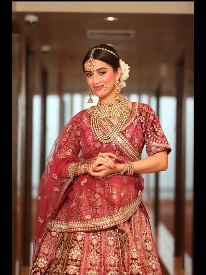 The complete royal bridal look. This image showcases a classic red lehenga with heavy gold embroidery, paired with traditional jewelry for a timeless aesthetic.