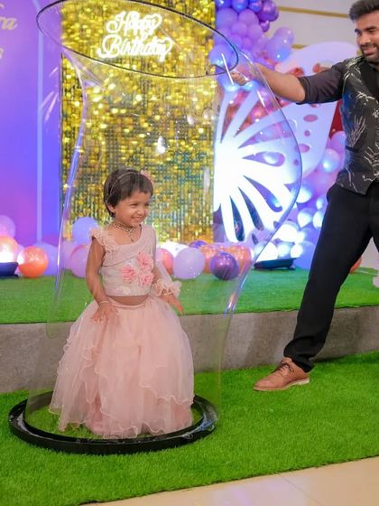 A magical moment for a first birthday party. This little girl is all smiles as she experiences being inside a giant bubble for the first time. It's a gentle and wonderful experience for the youngest of guests.