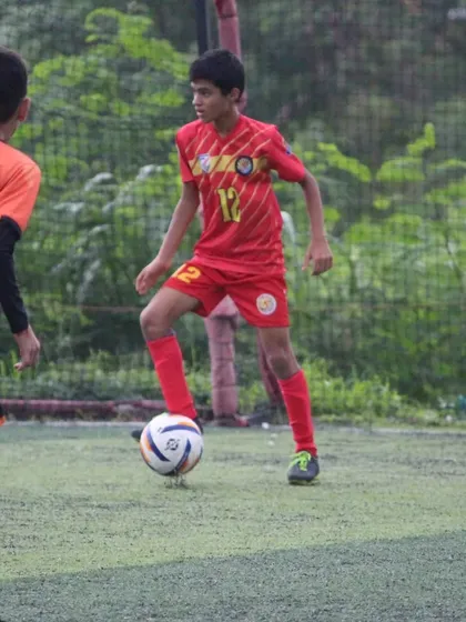 A U13 player focused on the ball during a match at the Grassroots Football Fiesta.