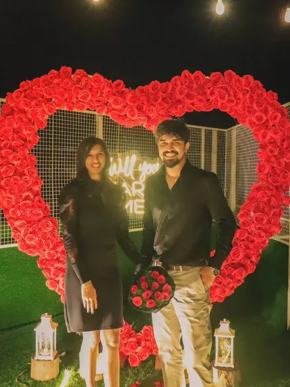 The perfect "yes" moment, captured forever. A happy couple stands before our oversized rose heart, showing the beautiful result of a perfectly planned surprise proposal.