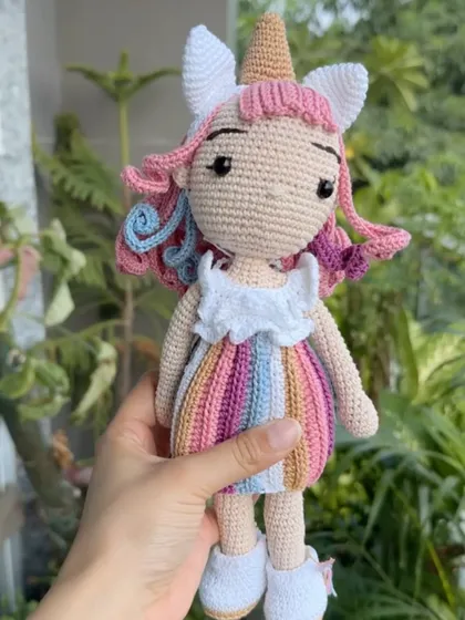 A close-up of the Bella unicorn doll, highlighting her colorful dress and unique, hand-stitched features.