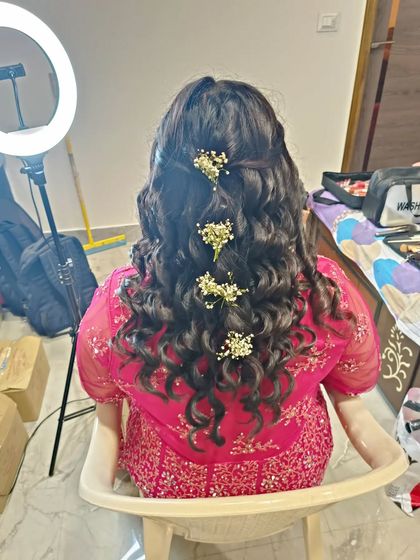 A half-up hairstyle with curls, adorned with sprigs of baby's breath. This is a delicate and romantic look, perfect for a daytime event.