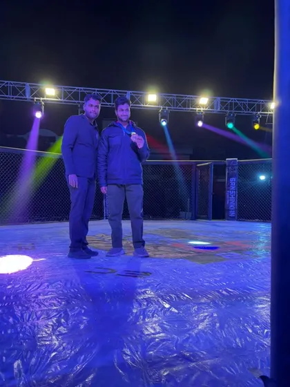 A coach and fighter posing in the empty octagon after a successful night of fights, reflecting on the victories earned.
