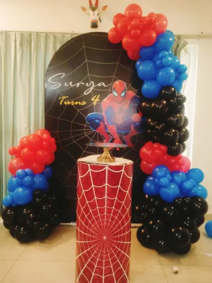 I can bring any superhero to the party with a custom themed setup. This Spider-Man decoration for a 4th birthday includes a web-themed backdrop with the birthday boy's name, a matching cake pedestal, and a dynamic balloon arch in classic red, blue, and black.