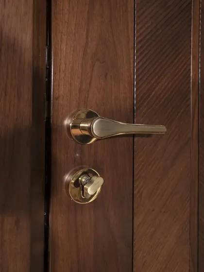 A close-up of the American walnut door with a ripped flute chevron design. The hardware is chosen to complement the rich, warm tones of the wood.