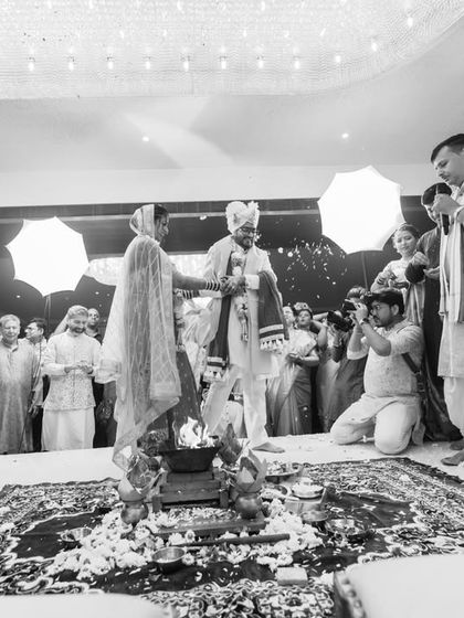A wide-angle, black and white shot of the wedding ceremony, showing the couple, the family, and our own team member capturing the moment. It's a snapshot of the entire scene.
