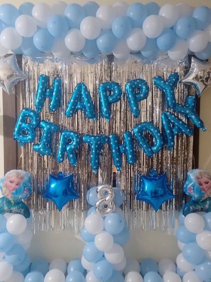 A simple "Happy Birthday" setup with a blue and white balloon frame and a silver fringe curtain.