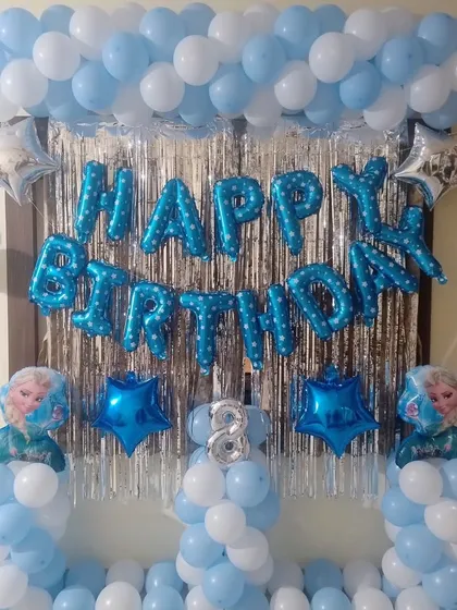 A simple "Happy Birthday" setup with a blue and white balloon frame and a silver fringe curtain.