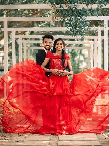 A dramatic "flying gown" shot in a garden. The red fabric creates a beautiful, wide arc, framing the couple perfectly.