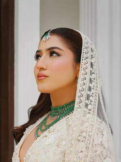 A close-up profile view that captures the bride's lit-from-within glow. The soft blush and highlighter create a beautiful, fresh bridal look that is both modern and timeless.