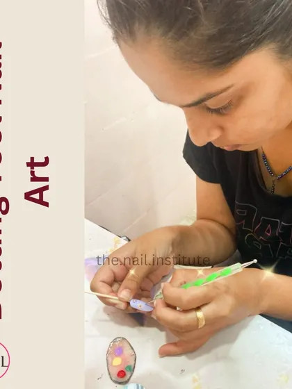 A student learns the basics of dotting tool nail art, creating a colorful polka dot design on a practice tip.