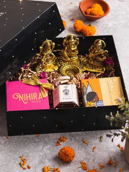 A traditional and elegant festive gift box. It contains brass idols of Lakshmi and Ganesh, along with Nihira sweets and honey, making it a perfect and auspicious gift for Diwali or a housewarming ceremony.