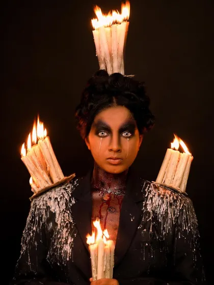 A direct, intense shot from the candle-themed fantasy portrait, focusing on the model's haunting white-eyed gaze.