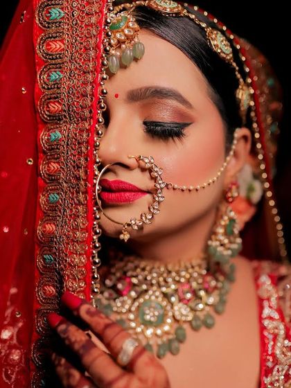 A captivating close-up. The winged eyeliner, bold red lip, and intricate nath create a powerful and unforgettable Rajwara bridal look.