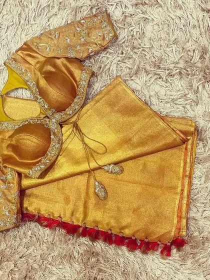 A stunning gold blouse with intricate silver and gold hand embroidery, featuring a unique back cutout design.