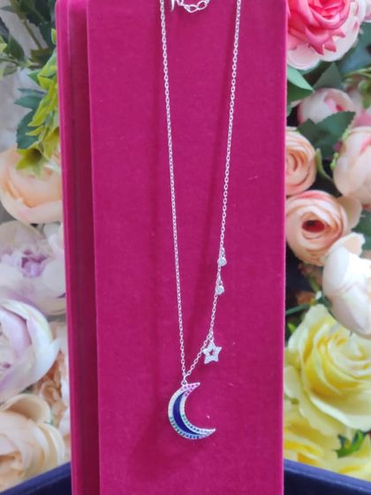 A celestial-themed necklace with a crescent moon and dangling stars, a dreamy and magical gift.