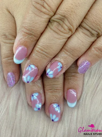 A lovely pastel set combining purple glitter, a French tip, and accent nails with a delicate blue floral pattern.