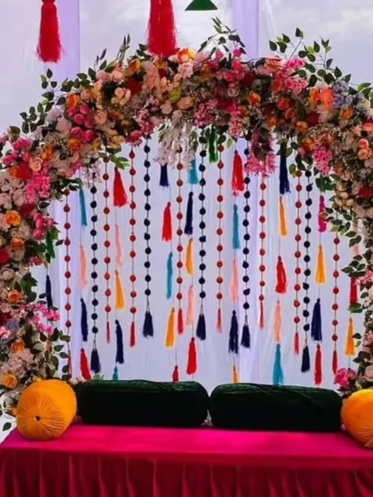 A beautiful floral arch with colorful hanging tassels creates a perfect frame for this Mehandi seating. The deep red gadda with green and yellow bolsters adds to the rich, festive look.