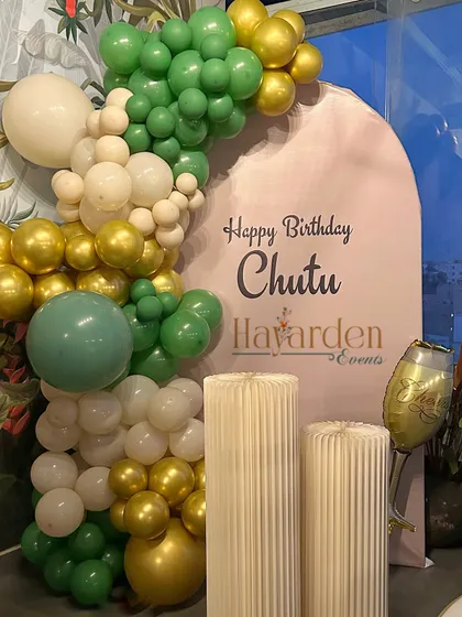 An arched backdrop in a lovely green and gold color scheme, perfect for a sophisticated birthday celebration.