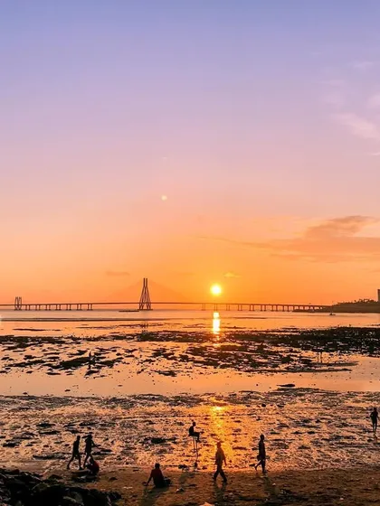A view of the sunset at a Mumbai beach with the Bandra-Worli Sea Link in the background.