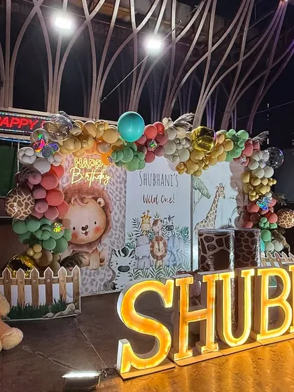 A closer look at Shubhani's "Wild One" jungle party. This setup features a custom backdrop with cute safari animals, a balloon arch in earthy tones, and large marquee letters spelling out the birthday girl's name.