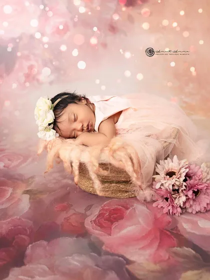 A dreamy and romantic newborn portrait. The baby is surrounded by a sea of pink flowers and soft light, creating a truly magical and ethereal image.