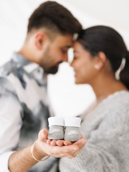 A creative and intimate shot focusing on the tiny baby shoes held in the parents' hands, symbolizing the new life they are about to welcome.