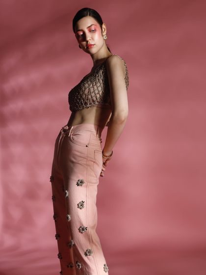 A profile shot that emphasizes the silhouette of the embellished trousers and woven top. The soft lighting and pose create a graceful and artistic mood.